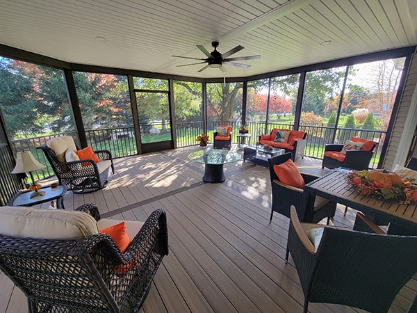 Screened-in composite deck — after: interior wide-angle view with ceiling fan, wicker furniture, and fall foliage through screens — Findlay, Ohio