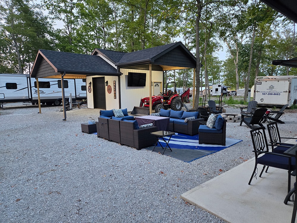Shed with larger gables — completed exterior with outdoor seating area and blue cushions — campground