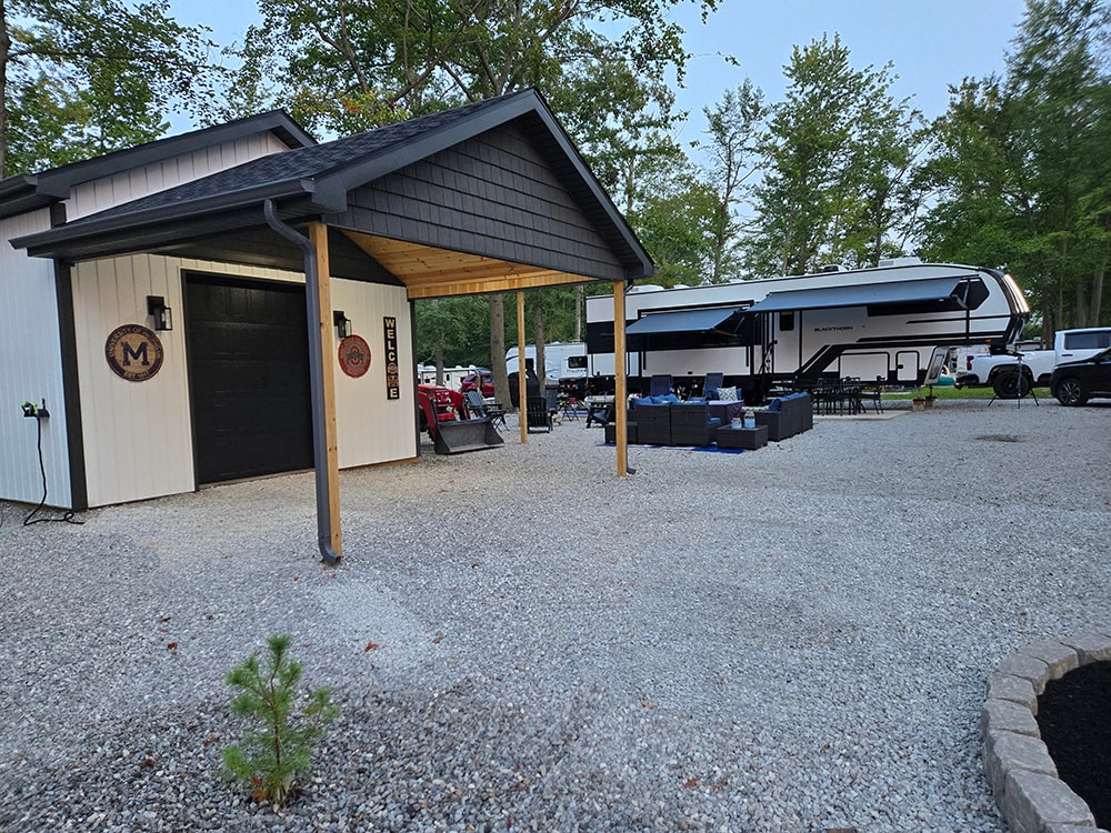 Shed with larger gables — completed front view with covered porch and gravel pad — campground
