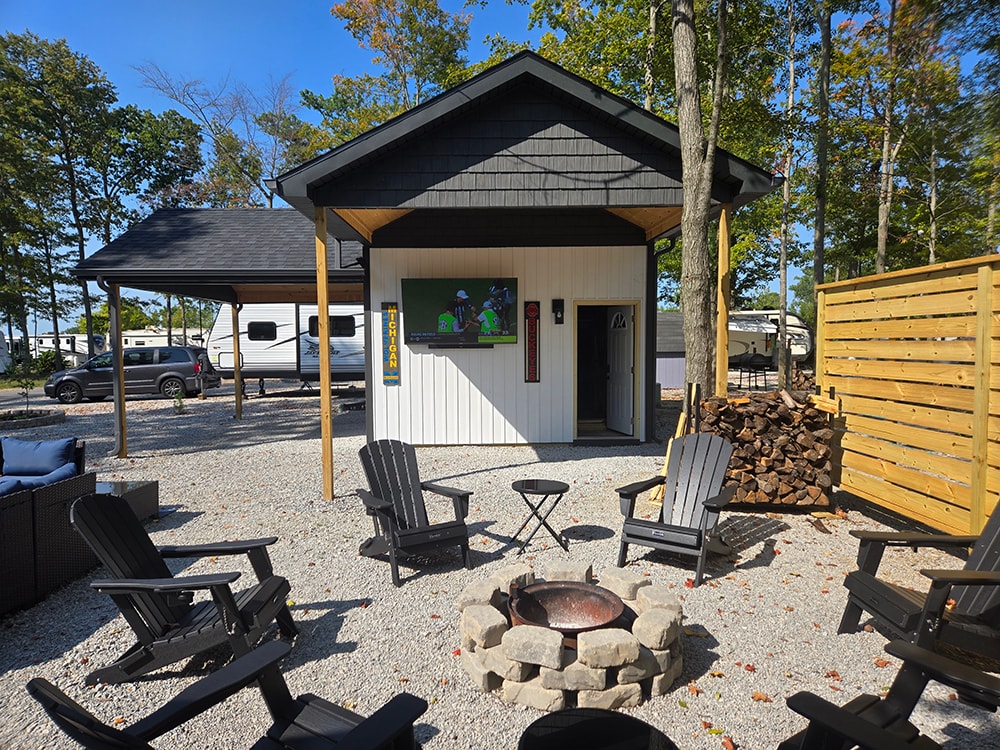 Shed with larger gables — completed exterior with fire pit and Adirondack chairs — campground