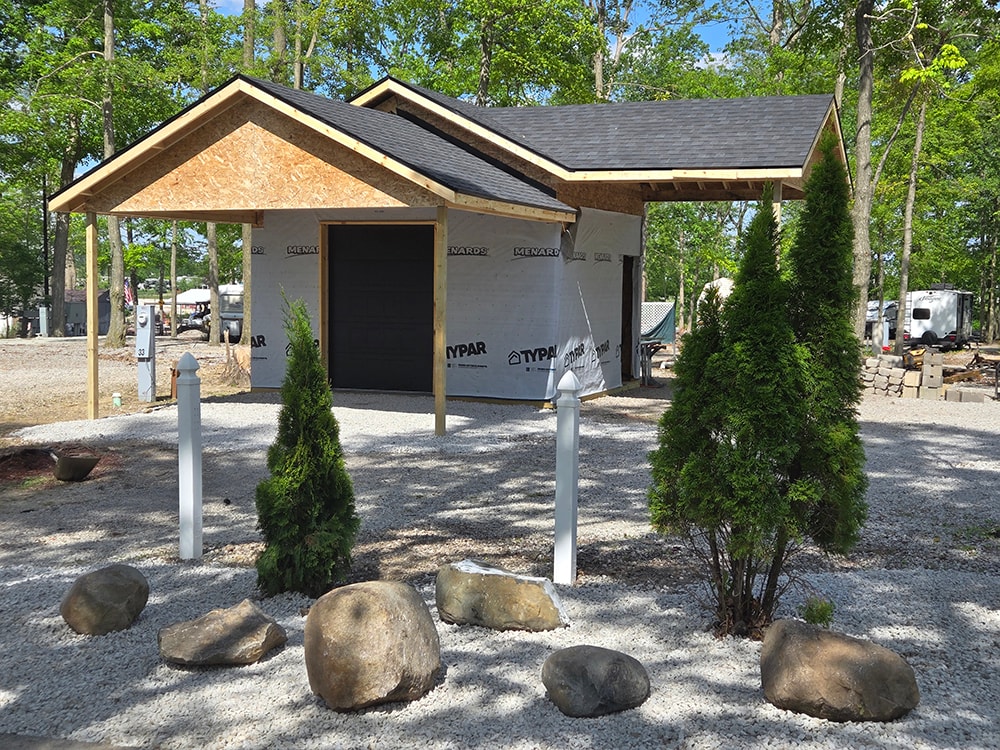 Shed with larger gables — framing stage front view with landscaping boulders — campground