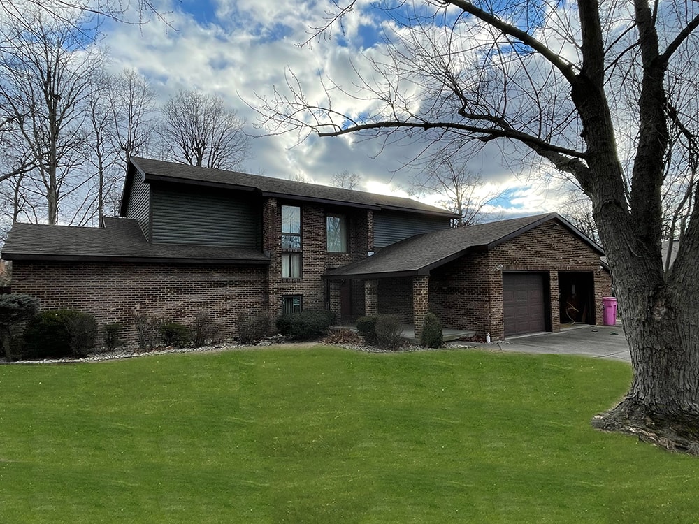 Siding job with brick — after: front view of brick home with new sage green vinyl siding on upper gables, Findlay, Ohio