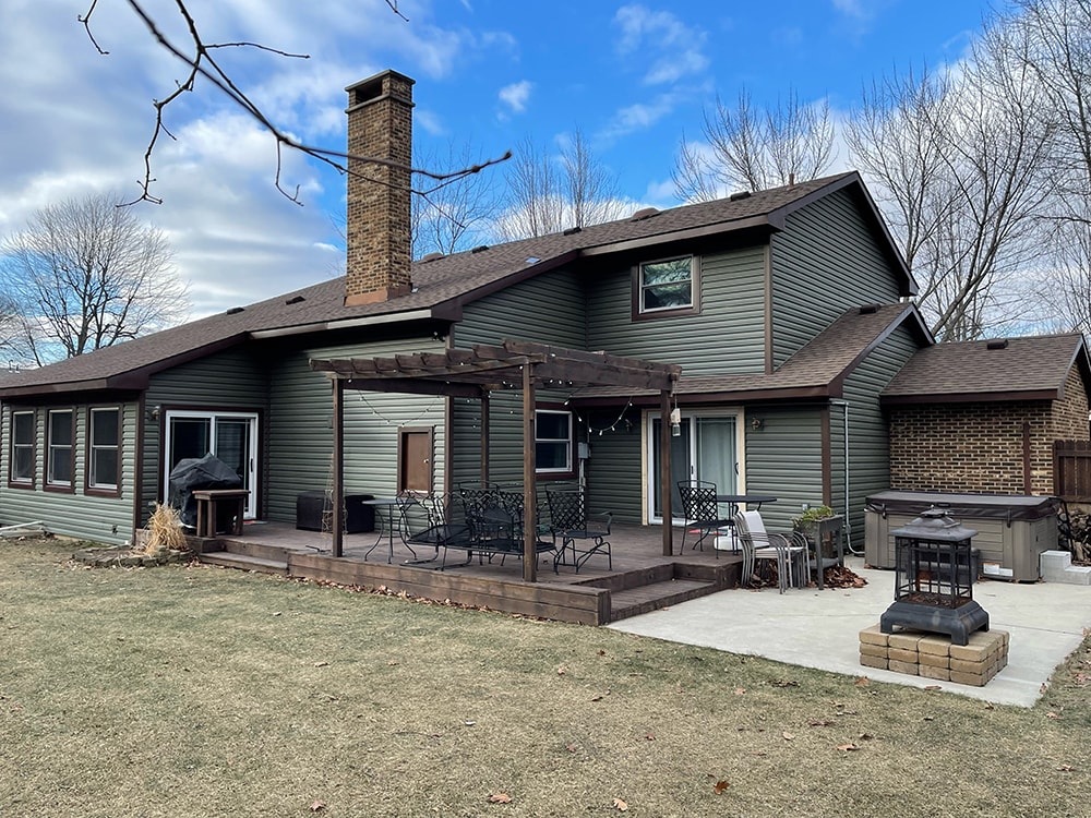 Siding job with brick — after: rear view of home with new sage green vinyl siding and pergola deck area, Findlay, Ohio