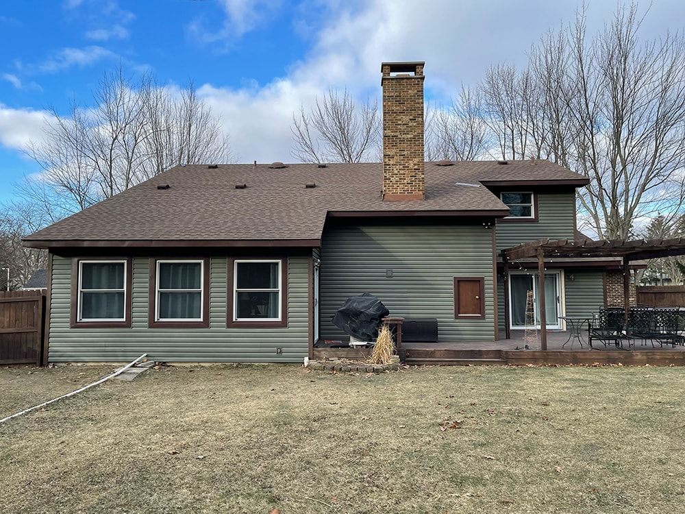 Siding job with brick — after: side rear view of home with new sage green vinyl siding and updated trim, Findlay, Ohio