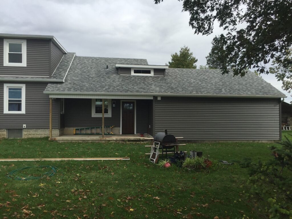 Siding and new windows Findlay — after: rear of completed home with new dark gray siding, covered porch, and white-trimmed windows, Findlay, Ohio
