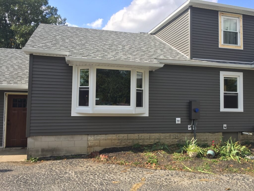 Siding and new windows Findlay — after: close-up of completed bay window with new dark gray siding and white trim, Findlay, Ohio