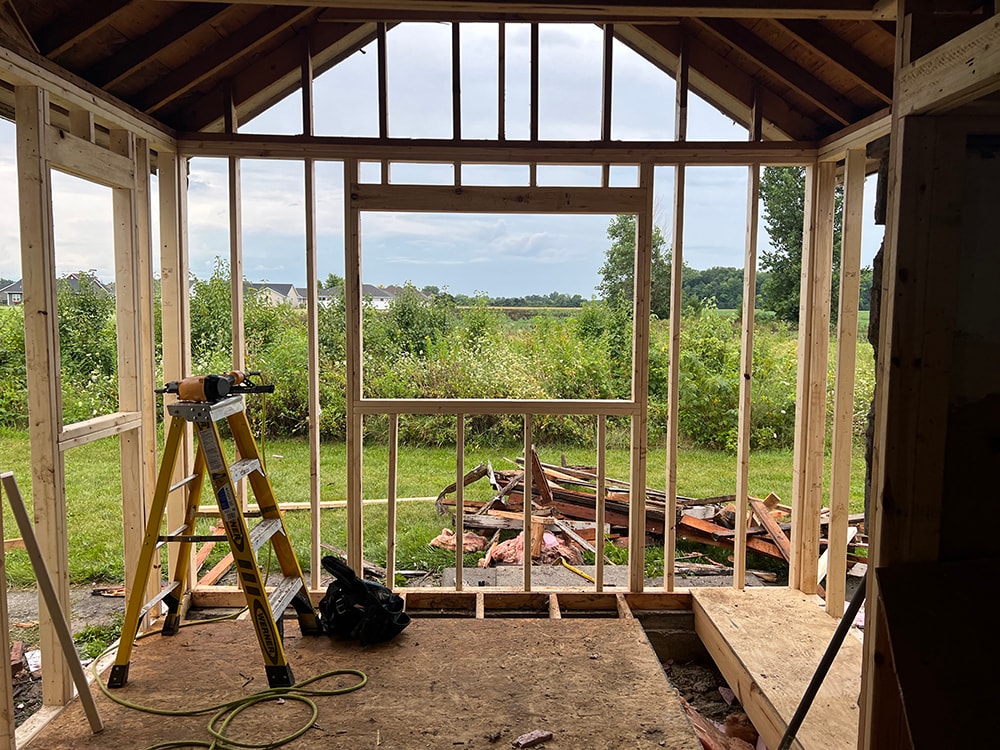 Small room reframe — new framing in progress, fresh lumber walls and floor framing with nail gun and ladder visible, Findlay, Ohio