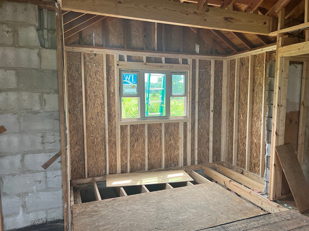 Small room reframe — new framing with OSB sheathing on walls and new window rough opening with floor joists exposed, Findlay, Ohio