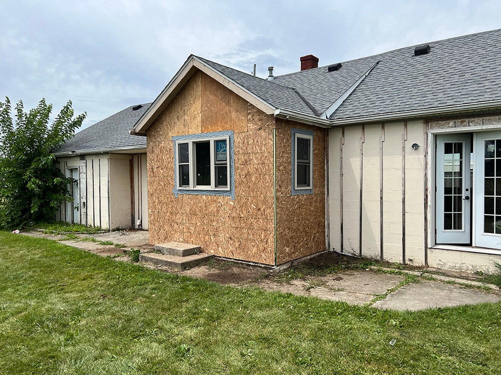 Small room reframe — exterior after, reframed addition with OSB sheathing and new windows installed, front view, Findlay, Ohio