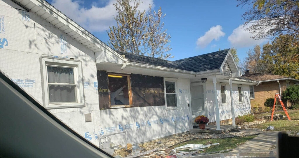 Stone siding Findlay — during: close-up of home wrapped in Findlay Siding house wrap with windows removed and Armstrong stone panels staged, fall foliage, Findlay, Ohio
