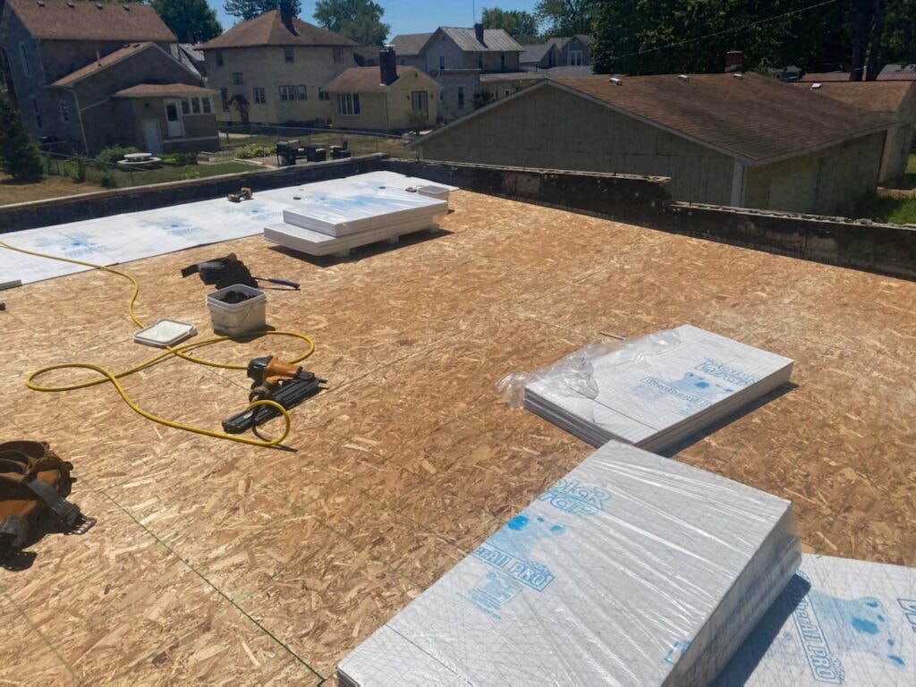 TPO roof replacement Findlay — during: new OSB roof decking fully installed with insulation boards and nail gun staged on surface, Findlay, Ohio