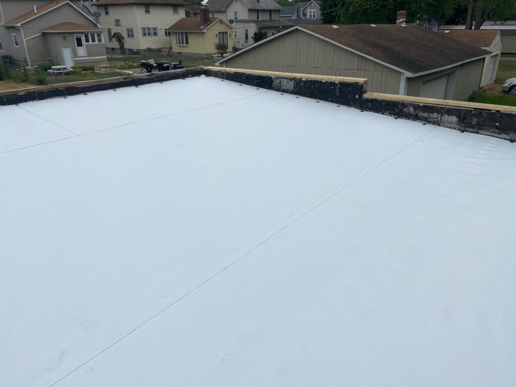 TPO roof replacement Findlay — after: completed white TPO membrane wide aerial view showing full roof surface with seam lines and new wood coping, Findlay, Ohio