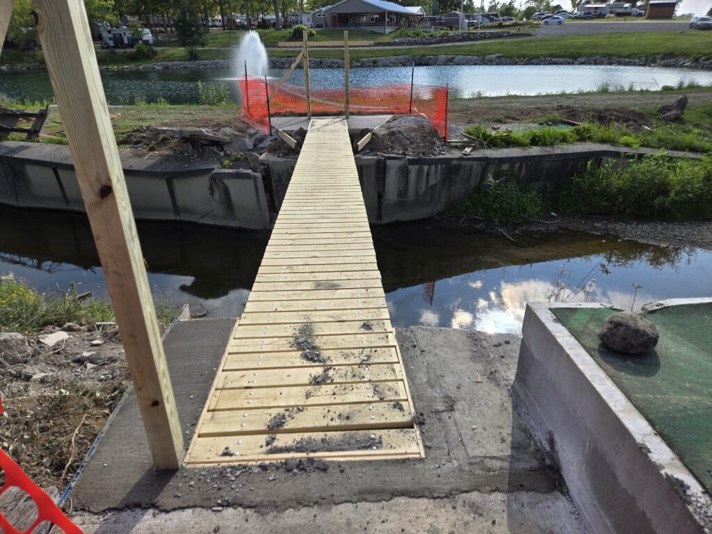 Steel and treated wood bridges — bridge 1 decking installed over water with safety fencing still up — Findlay, Ohio
