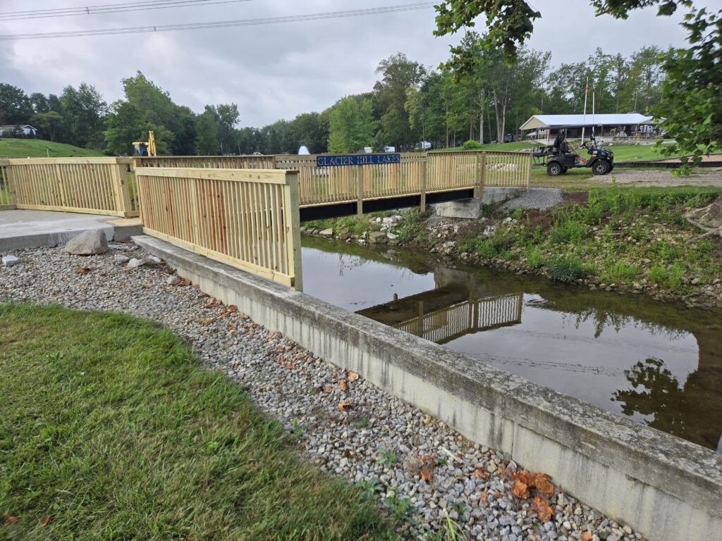 Steel and treated wood bridges — bridge 2 completed side view with concrete approach and playground in background — Findlay, Ohio